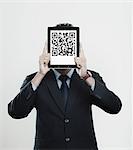 Businessman holding a digital tablet in front of his face with 2D barcode on it