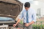 Businessman examining his broken down car, Gurgaon, Haryana, India