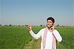 Farmer talking on a mobile phone in the field, Sonipat, Haryana, India