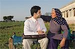 Businessman sitting with his mother in the field, Sonipat, Haryana, India