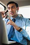 Bengali businessman using a laptop and talking on a mobile phone in a car