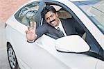 South Indian businessman driving the car and waving hand