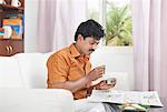 South Indian man reading a newspaper and having breakfast