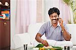 South Indian man having food and talking on a mobile phone