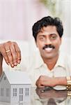 South Indian man putting money in a model home