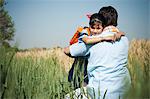 Farmer hugging his daughter in the field, Sohna, Haryana, India
