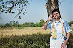 Farmer talking on a mobile phone in the field, Sohna, Haryana, India
