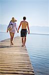 Croatia, Young couple in swimwear walking across boardwalk, rear view