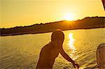 Croatia, Adriatic Sea, Young man on sailboat at sunset, leaving water