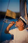 Croatia, Senior man with captain's hat drinking, side view