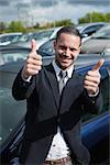 Businessman raising his thumbs while smiling outdoors