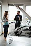 Businessman presenting a car to a woman in a garage