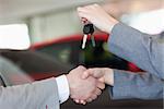 Close up of a woman shaking hand to a man in a dealership