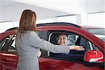 Businesswoman presenting something to a man in a dealership