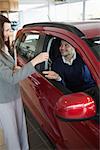 Businesswoman giving car keys to a customer in a garage