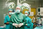 Surgeon joining his hand with two interns behind him in a surgical room