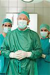 Surgeon joining his hand with interns behind him in a surgical room