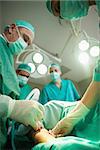 Team of surgeons using scalpel to open a patient in a surgical room