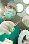 Surgeon smiles as he takes a surgical scissors in a surgical room