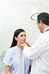 Doctor touching the neck of a patient in an examination room