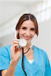 Smiling nurse holding a stethoscope in a hallway