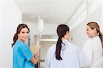 Nurse smiling while standing in a hallway with a patient and a doctor in a hospital