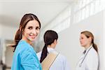 Smiling nurse  while standing in a hallway with a patient and a doctor in a hallway