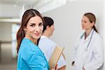 Nurse in a hallway with a doctor and a patient while holding files in a hospital