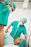 Two doctors looking at a patient in hospital corridor