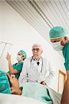 Doctor and surgeon looking at a female patient in hospital ward