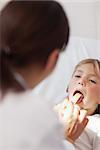 Doctor examining the mouth of a child in hospital ward