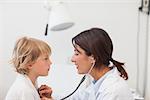 Doctor auscultating a child with a stethoscope in examination room