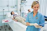 Nurse standing while looking at a clipboard in hospital ward