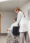 Doctor pushing a wheelchair in hospital ward