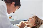 Doctor auscultating the mouth of a child in an examination room