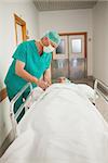 Patient lying on a medical bed next to a surgeon in hospital corridor