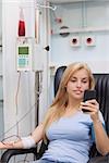 Female blood donor looking at her mobile phone in hospital ward