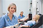 Nurse holding a clipboard next to a transfused patient in hospital ward