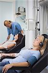 Female patient listening music while being transfused in hospital ward