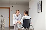 Patient sitting on a wheelchair in front of a doctor in hospital hallway