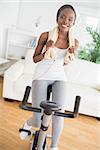 Black woman doing exercise bike while wearing a towel in a living room