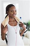 Black woman wearing a towel while holding a bottle in a living room