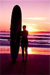 Surfer girl with surfboard at sunset beach
