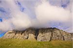 Picturesque cliff with clouds forming on the top, island of Vaeroy, Lofoten, Norway