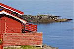 Picturesque red fishing hut on the coast of fjord on Lofoten islands in Norway