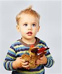 Studio portrait of a one year old baby boy on gray with Christmas toy in hand.