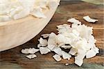 flakes of shredded coconut on a rustic wooden table and in a bowl