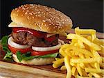 Photo of a hamburger and french fries on a wooden board.