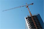 Construction site of modern office buildings with high crane on blue sky background