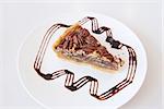 Pecan Nuts Pie with Slice with Dark Chocolate Drizzle on White Plate